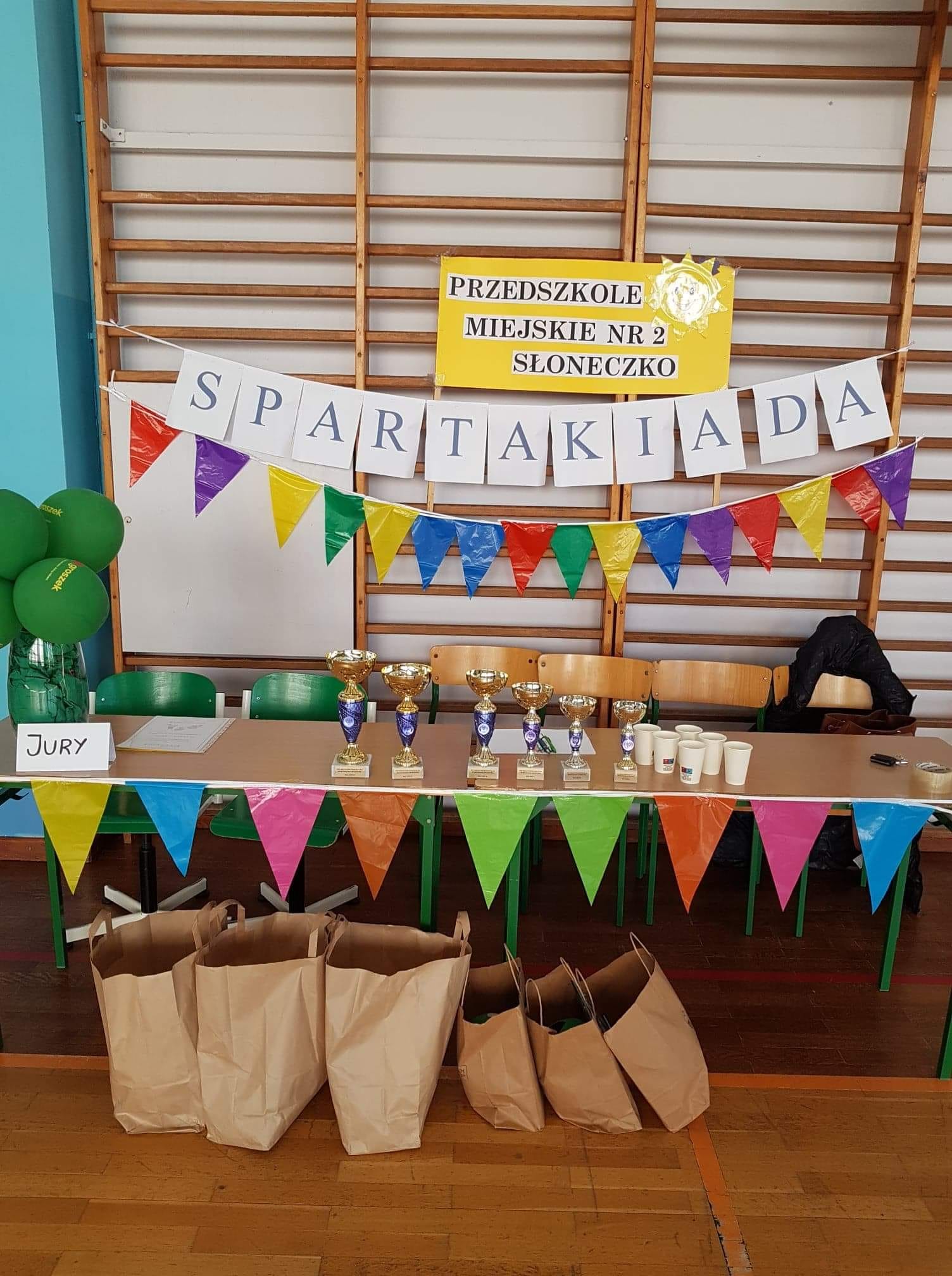 St&oacute;ł na kt&oacute;rym stoją puchary, na drabince zawieszony napis Spartakiada.