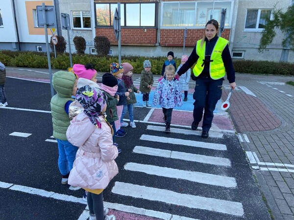 Strażnik Miejski przeprowadza dziecko przez pasy w miasteczku rowerowym.