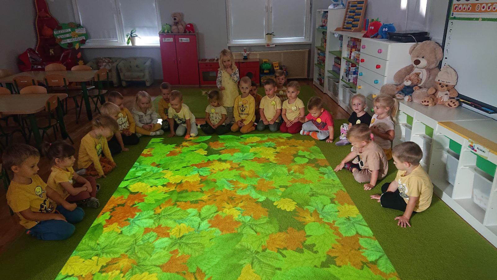 Dzieci siedzą w p&oacute;łkolu na magicznym dywanie.