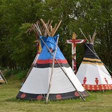 Na trawie stoją dwa namioty indiańskie.