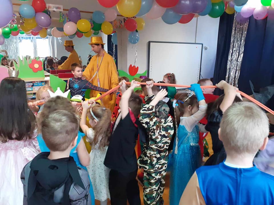 Dzieci przebrane w stroje karnawałowe biorą udział w zabawie z animatorem