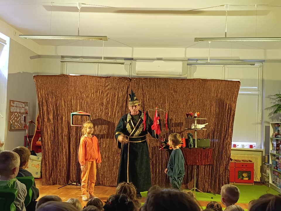 Magik wykonuje sztuczkę razem z dwojgiem dzieci.