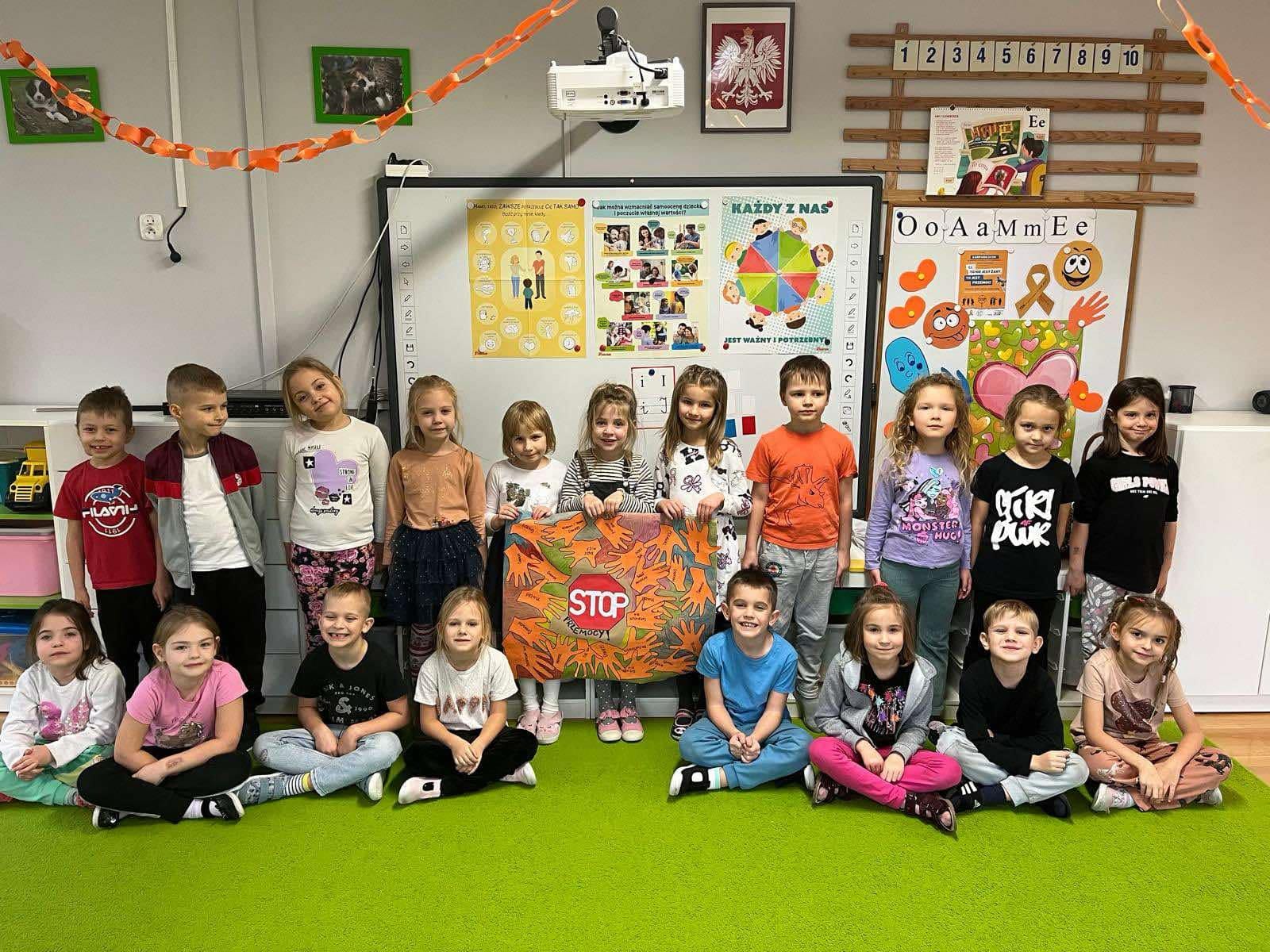 Dzieci stoją w grupie z plakatem przeciwko przemocy.