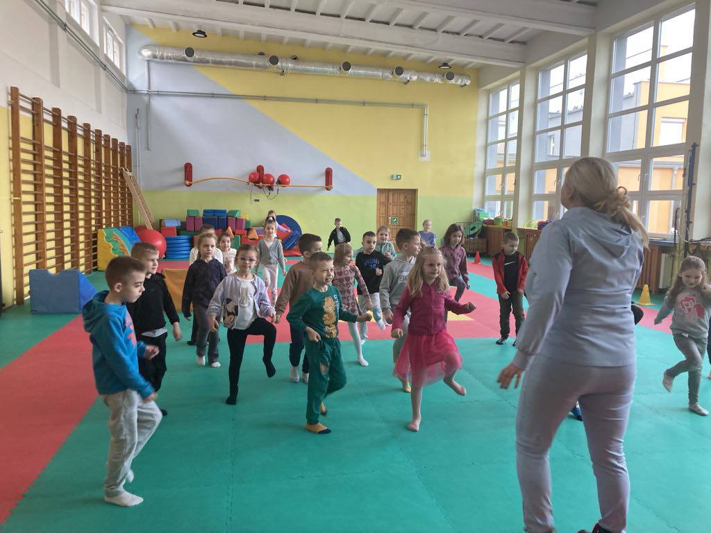 Dzieci ćwiczą na materacach na sali gimnastycznej w szkole.