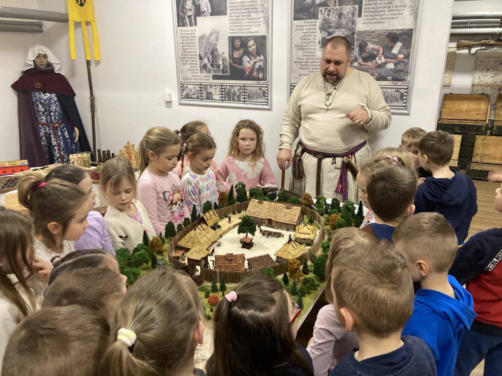 Dzieci stoją wok&oacute;ł stołu, na kt&oacute;rym jest makieta grodu.