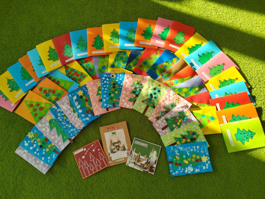 Na dywanie leżą wykonane przez dzieci kartki świateczne.