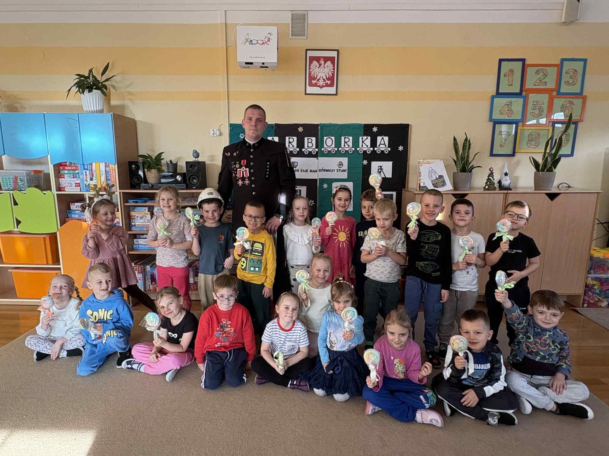 Dzieci wraz z G&oacute;rnikiem stoją w grupie i pozują do zdjęcia.