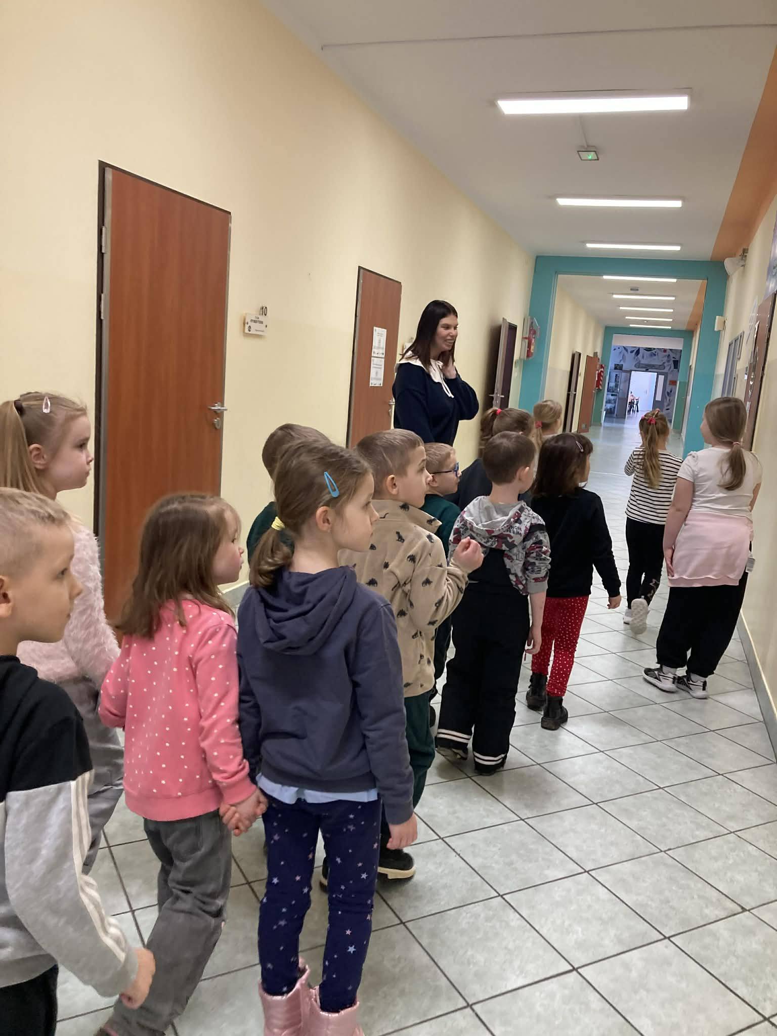 Dzieci idą szkolnym korytarzem.