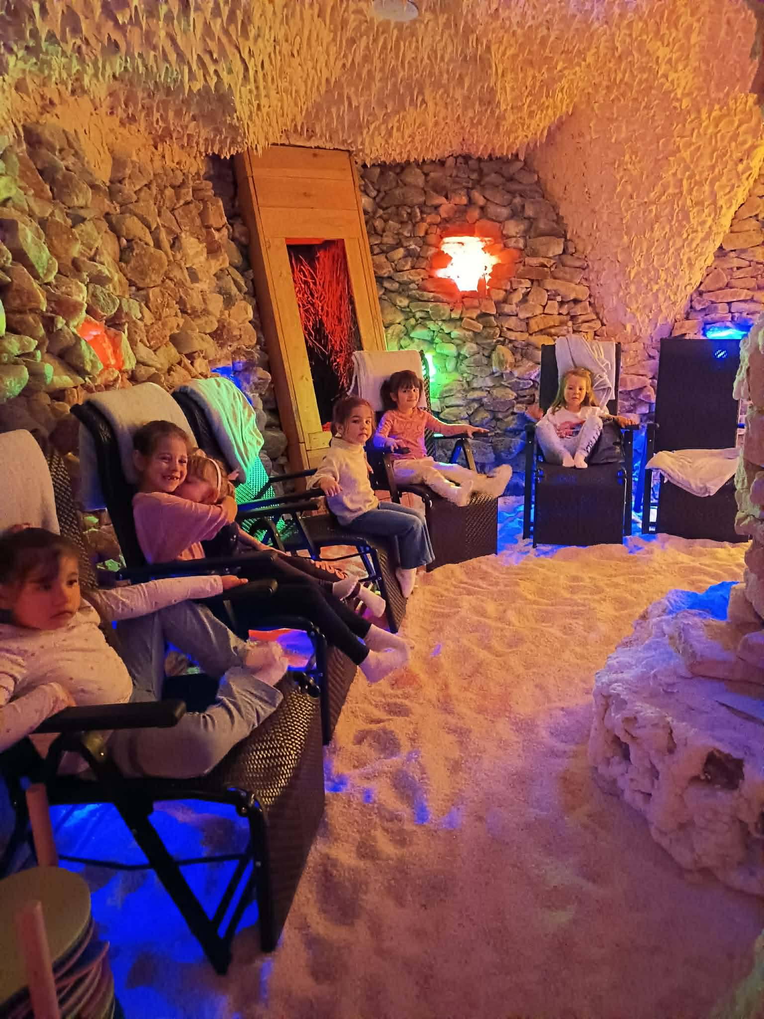 Dzieci siedzą na leżakach w grocie solnej.
