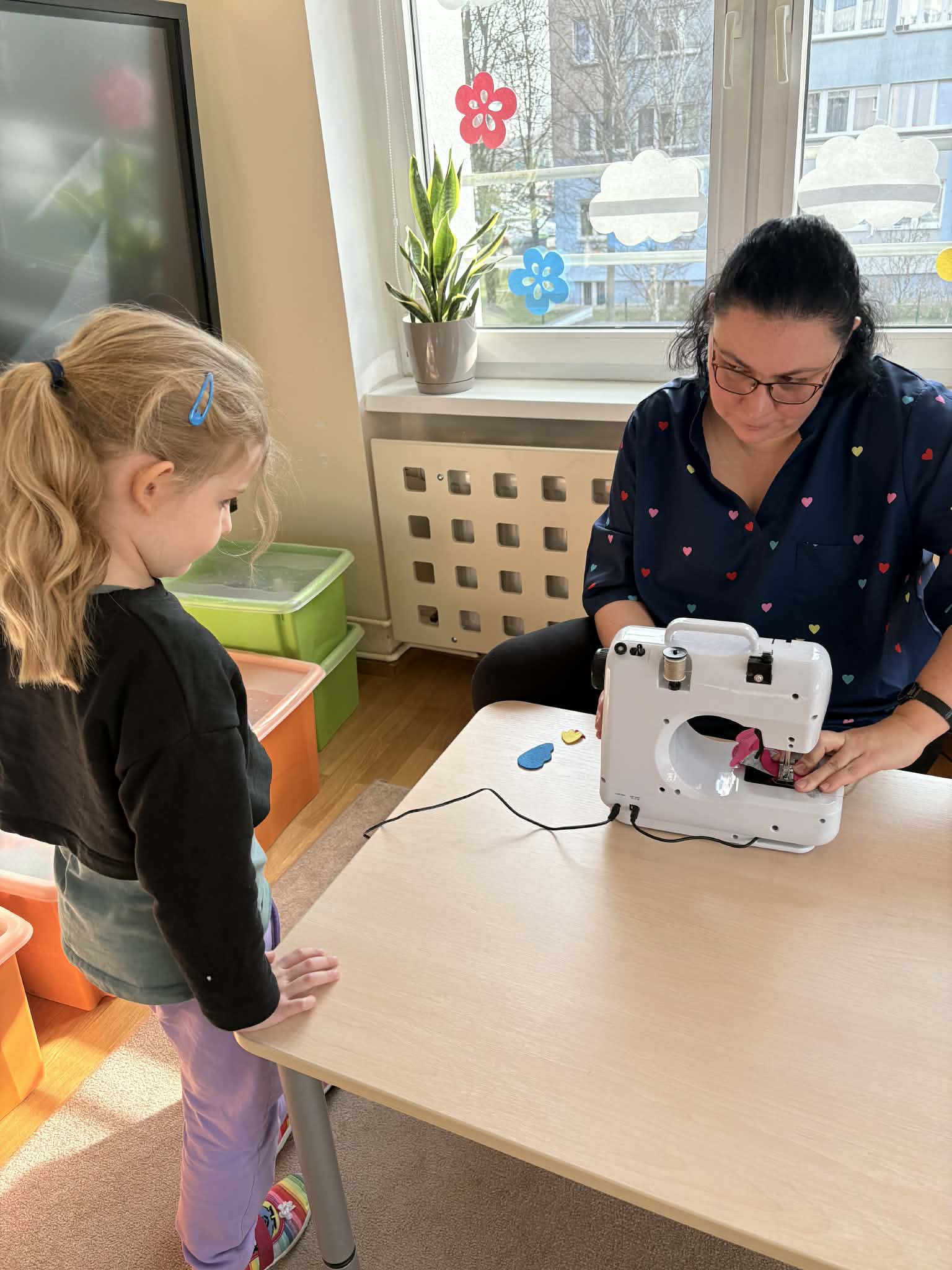 Pani szyje na maszynie dziewczynka stoi obok.