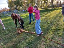 Dzieci układają na trawie ziemniaki w rzędzie.