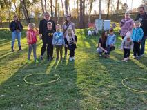 Dzieci rzucają do obręczy położonej na trawie ziemniakami.