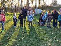 Dzieci rzucają do obręczy położonej na trawie ziemniakami.