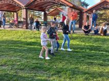 Dzieci wraz z rodzicami przenoszą na łyżce ziemniaka.