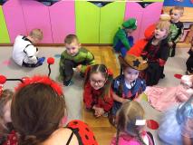 Dzieci przebrane w stroje karnawałowe kucają.