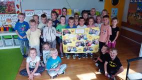 Dzieci stoją w grupie trzymając w ręku plakat wykonane z okazji Dnia Uśmiechu.