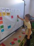 Dziecko przypina do tablicy kolorowe buzie.
