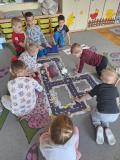 Grupa dzieci bawi się na dywanie robotem edukacyjnym.