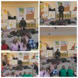 Żołnierz pokazuje dzieciom sprzęt wojskowy dzieci siedzą w kole.