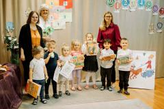 Dzieci pozują do zdjęcia trzymając książki i dyplomy.