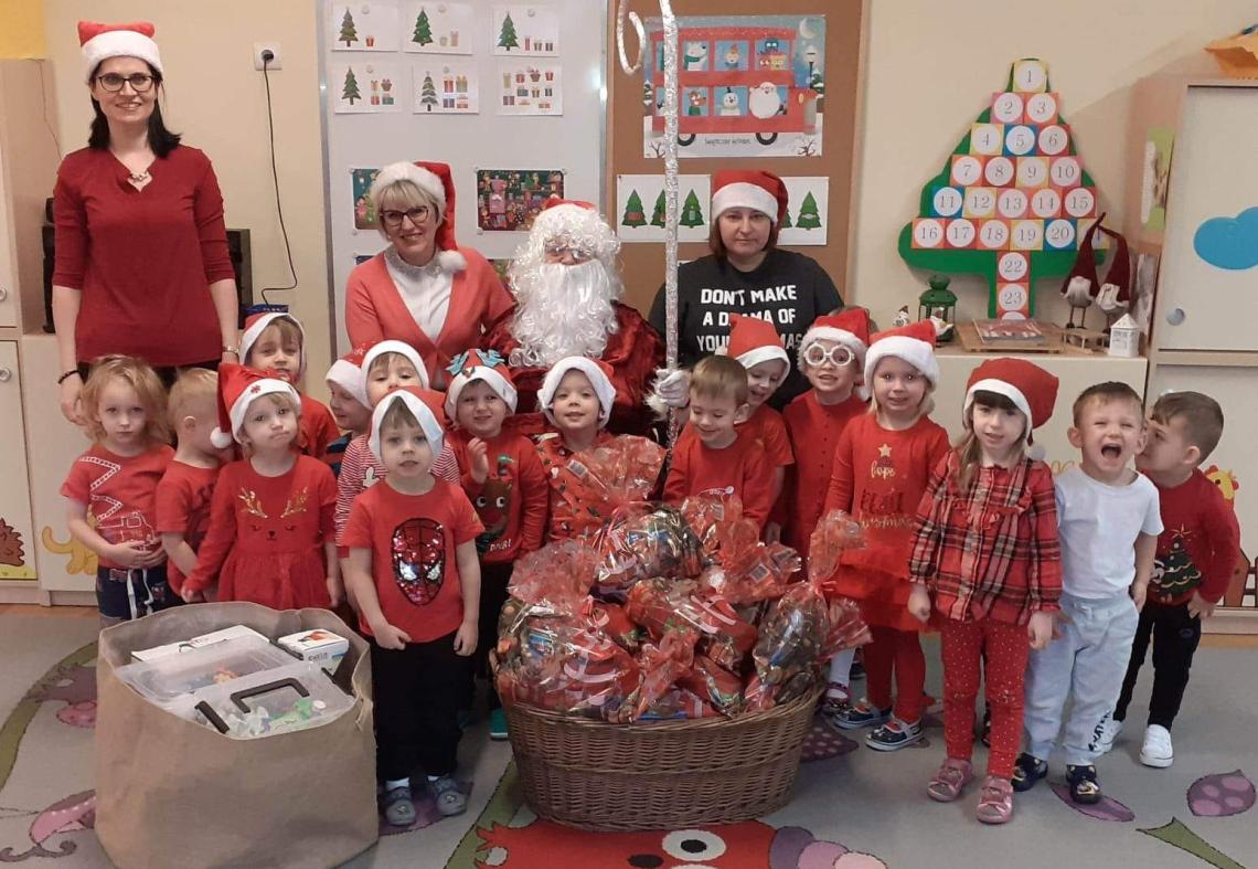 Dzieci pozują do zdjęcia z Mikołajem i paniami.