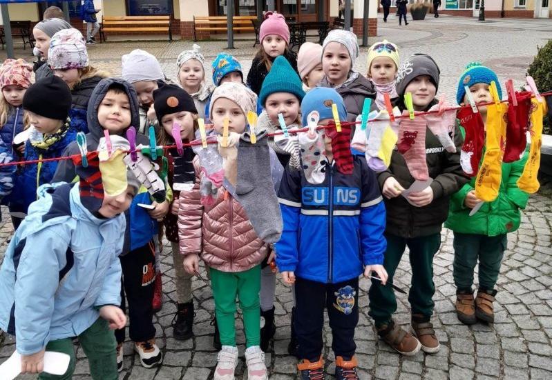 Dzieci stoją na Rynku przed nimi sznurek z przypiętymi skarpetkami