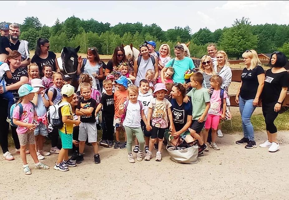 Dzieci wraz z rodzicami stoją w grupie na powietrzu.