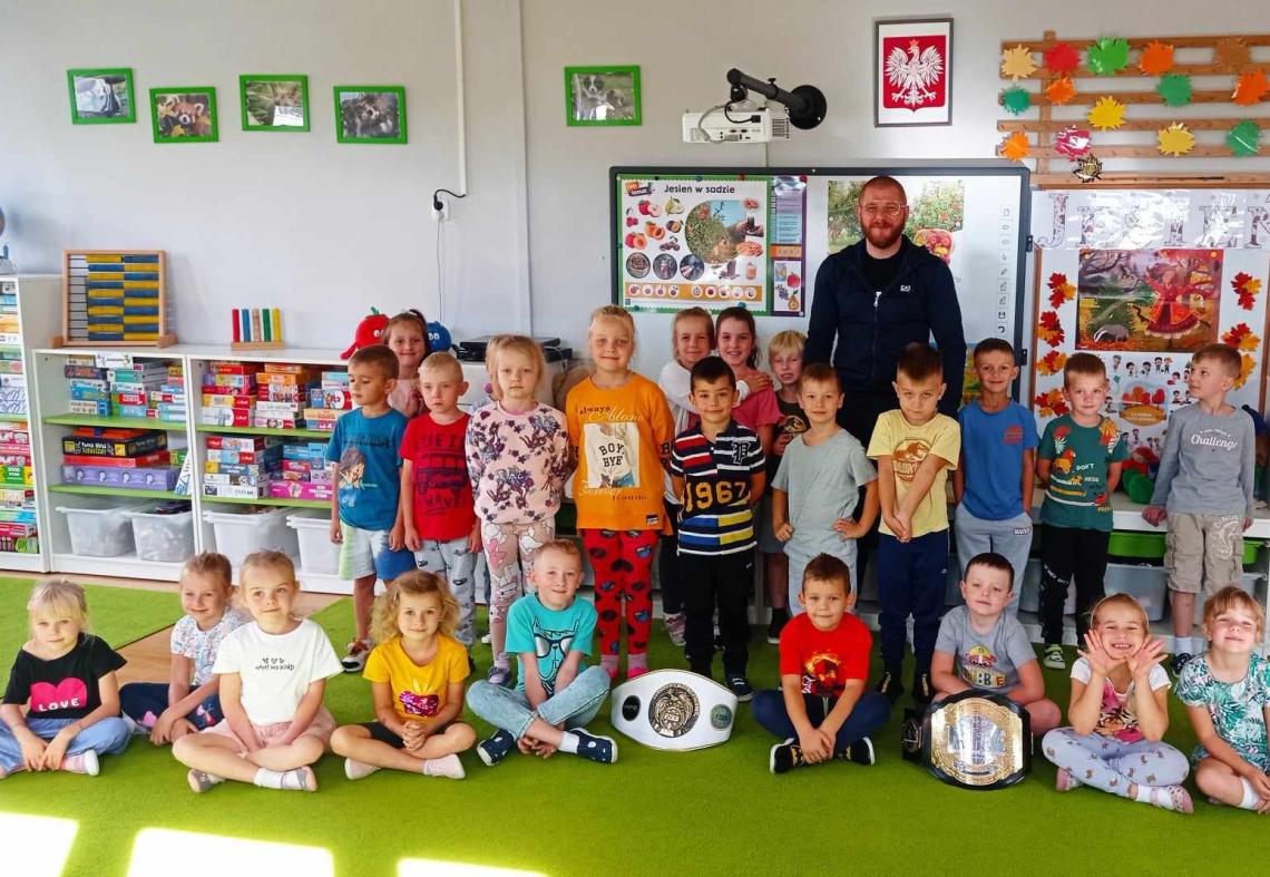 Sportowiec z grupą dzieci pozuje do zdjęcia.