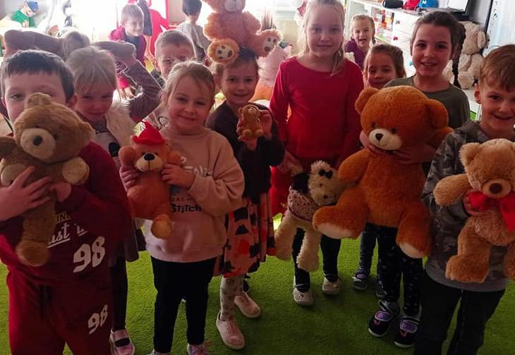 Dzieci stoją w grupie trzymając w rękach misie.