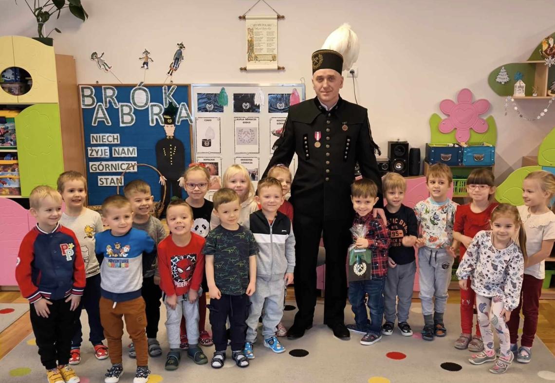 Dzieci stoją w grupie z górnikiem.