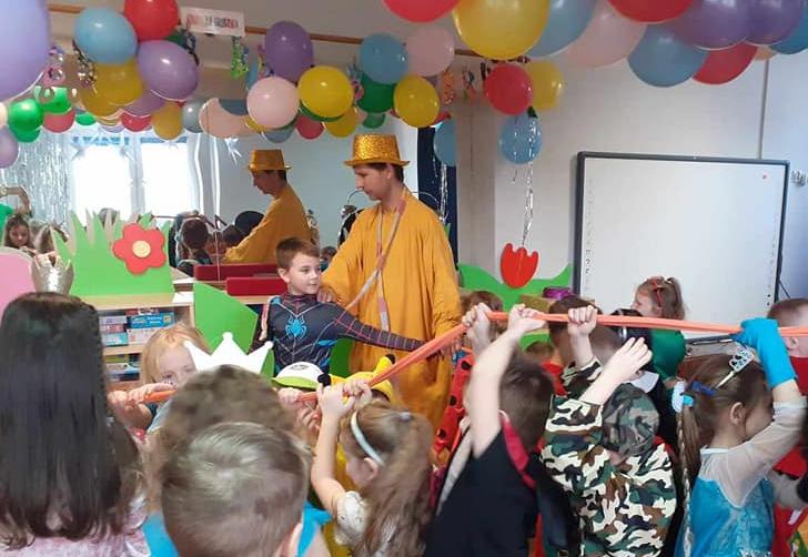 Dzieci przebrane w stroje karnawałowe biorą udział w zabawie z animatorem