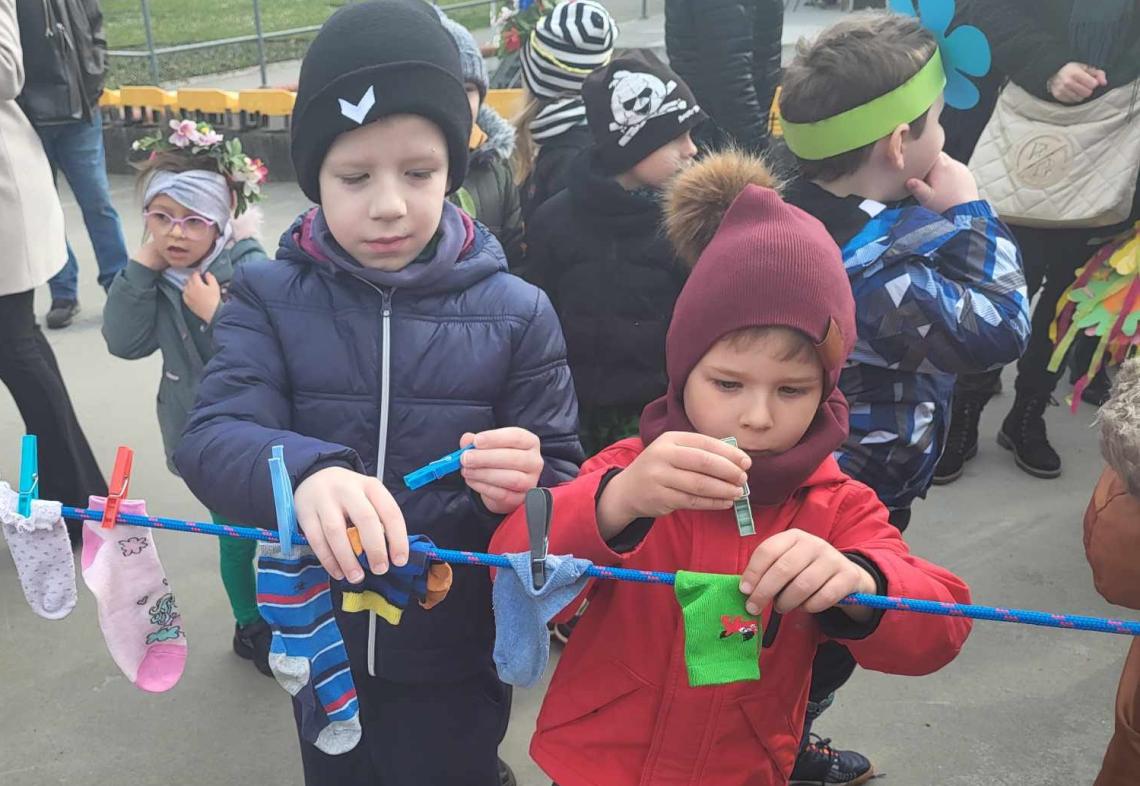 Dwóch chłopców przyczepia skarpetki do sznurka na rynku.