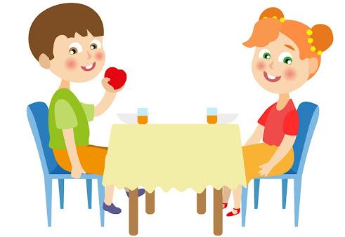 Dwoje dzieci siedzi przy stole i jedzą.