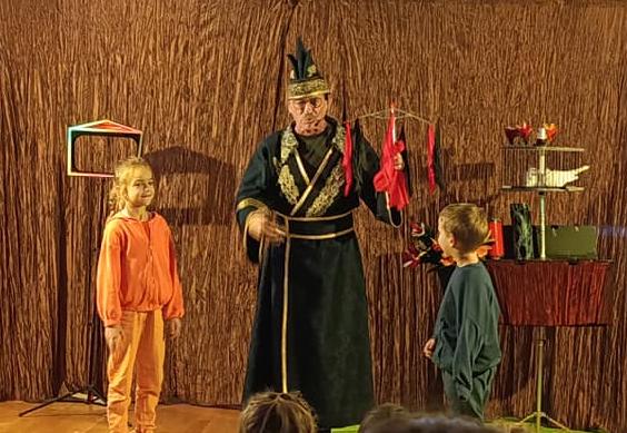 Magik wykonuje sztuczkę razem z dwojgiem dzieci.