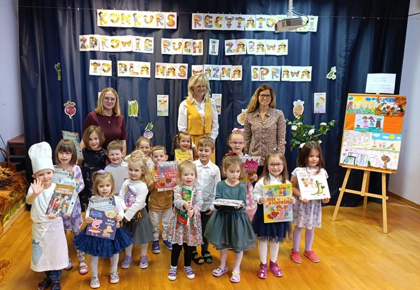 Dzieci stoją w grupie razem z panią dyrektor oraz nauczycielkami trzymając w rękach dyplomy i nagrody książkowe