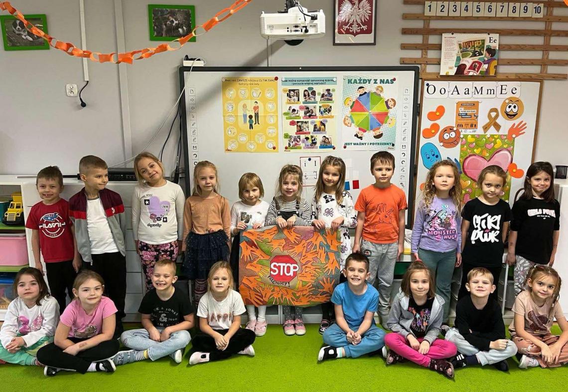 Dzieci stoją w grupie z plakatem przeciwko przemocy.