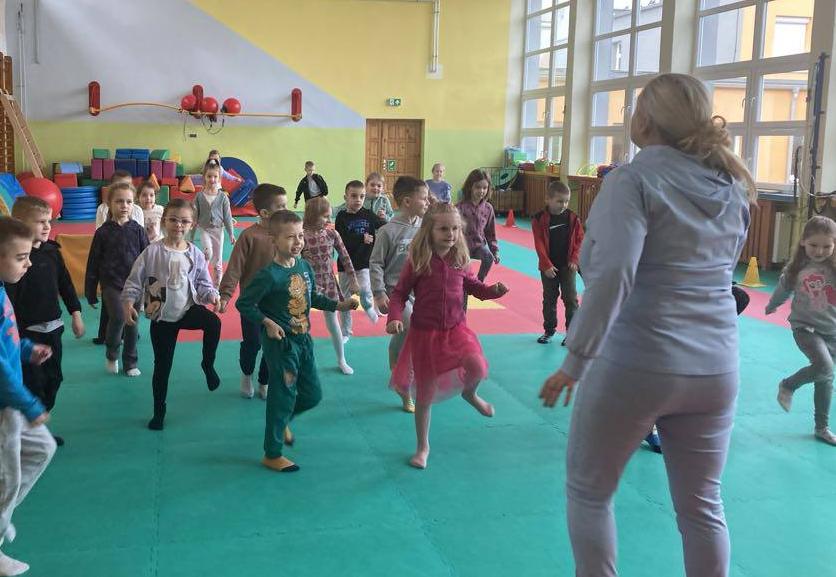 Dzieci ćwiczą na materacach na sali gimnastycznej w szkole.