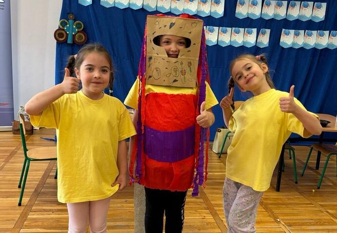 Dwoje dzieci stoi ubranych w żółte koszulki jedno dziecko ma strój zrobiony z kartonu.