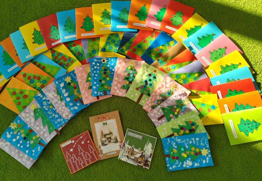 Na dywanie leżą wykonane przez dzieci kartki świateczne.