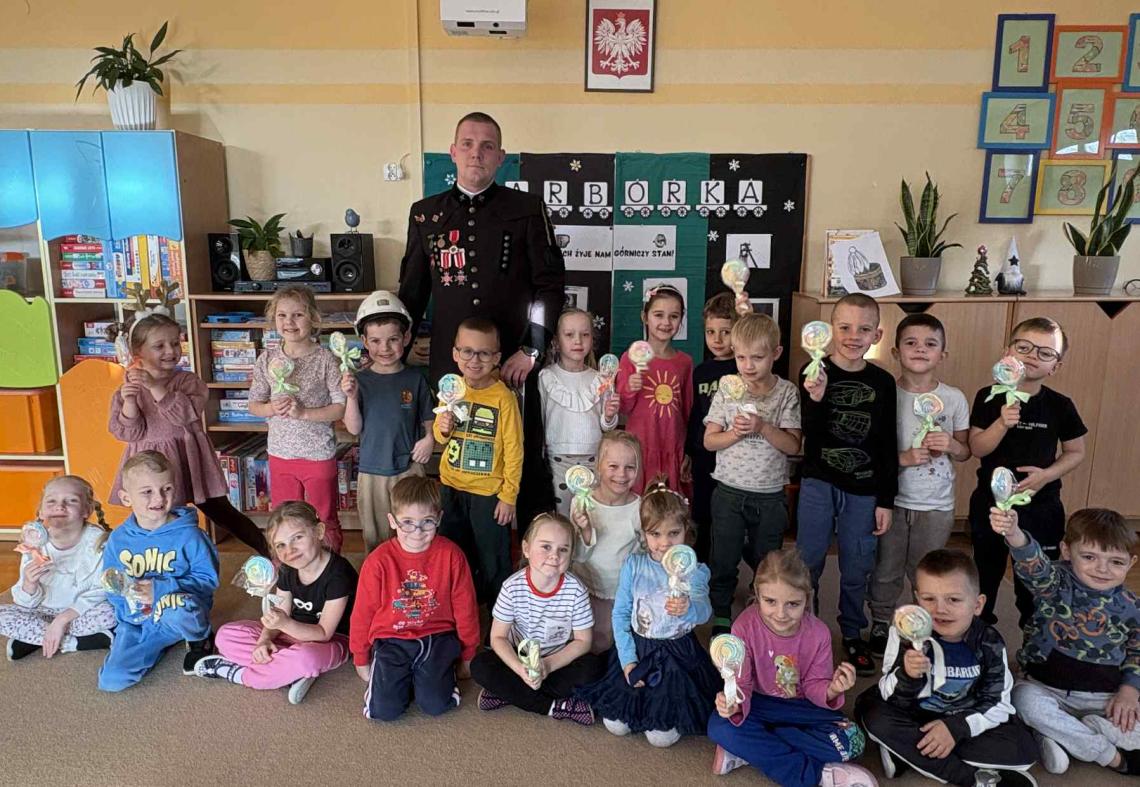 Dzieci wraz z Górnikiem stoją w grupie i pozują do zdjęcia.