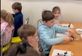 Dzieci siedzą przy stole dekorując pierniki