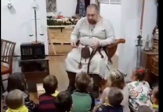 Dzieci siedzą na dywanie słuchając historycznych opowieści.