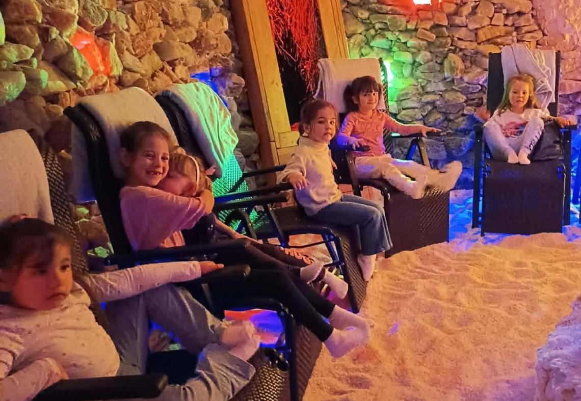 Dzieci siedzą na leżakach w grocie solnej.