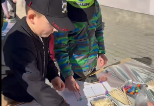 Dwóch chłopców stoi przy stoliku i z tworzy figury geometryczne z plasteliny i patyczków.