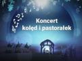 Napis koncert kolęd i pastorałek, białe nuty, na dole szopka z Jezusem
